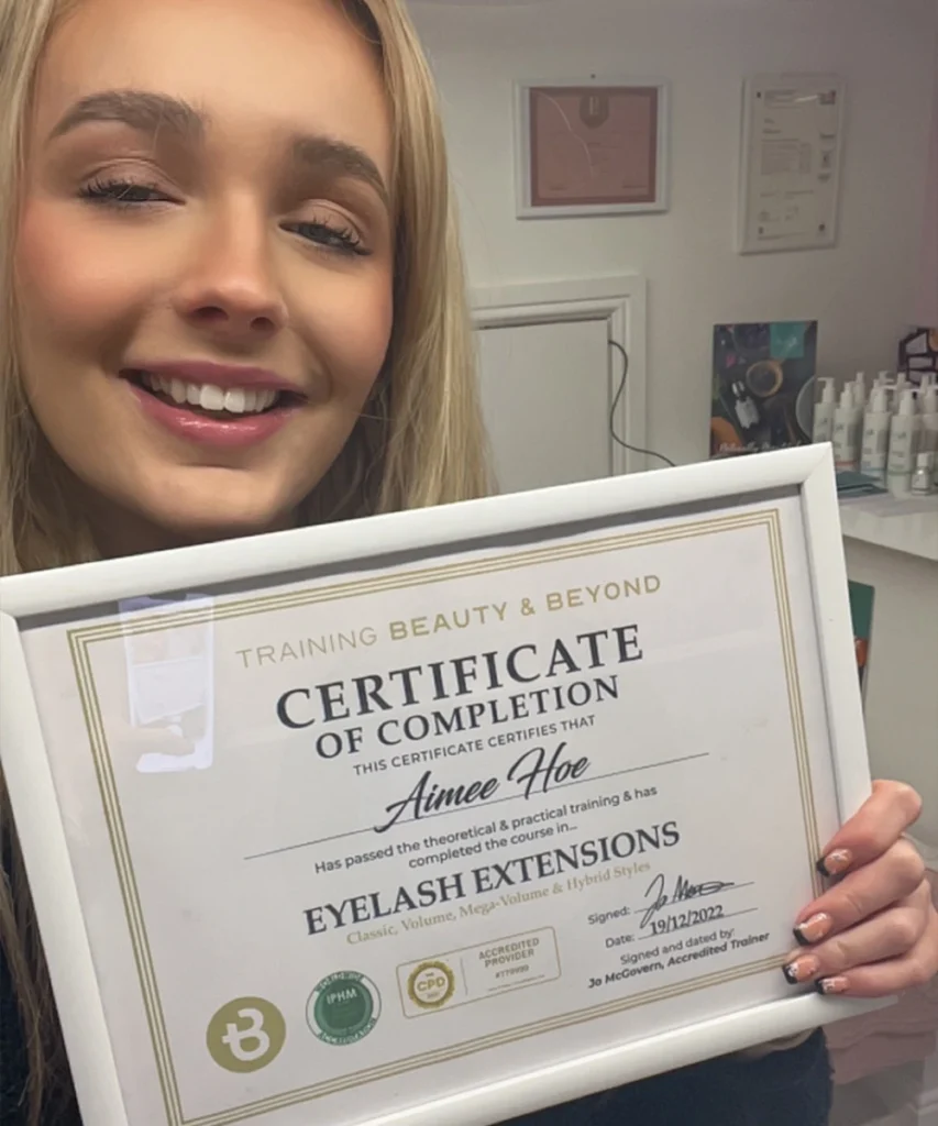 Student Aimee holding her accredited eyelash extension certificate